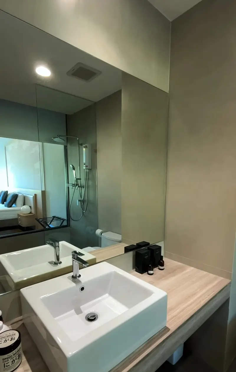 White basin on a wooden counter below a large mirror