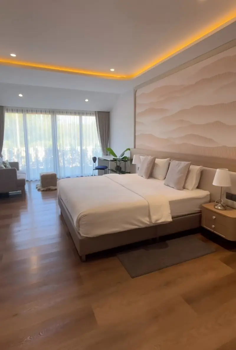 Bed against a wavy patterned feature wall, with tall curtained windows at the far end