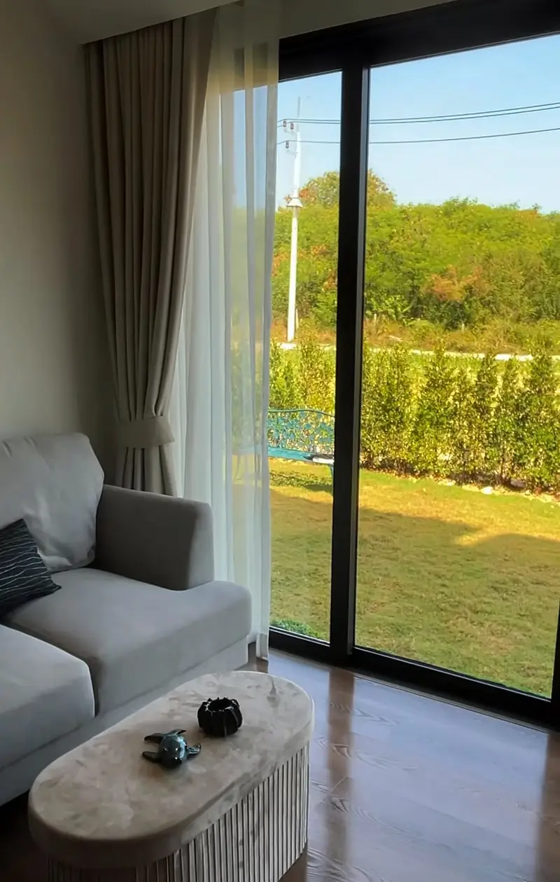 Grey sofa and a low table beside a full-height glass door looking out onto a lawn